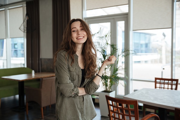 Attractive smiling Ukrainian girl standing near a table in a coffee shop
